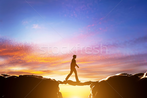 Man walking over precipice between mountains, another man being a bridge Stock photo © photocreo