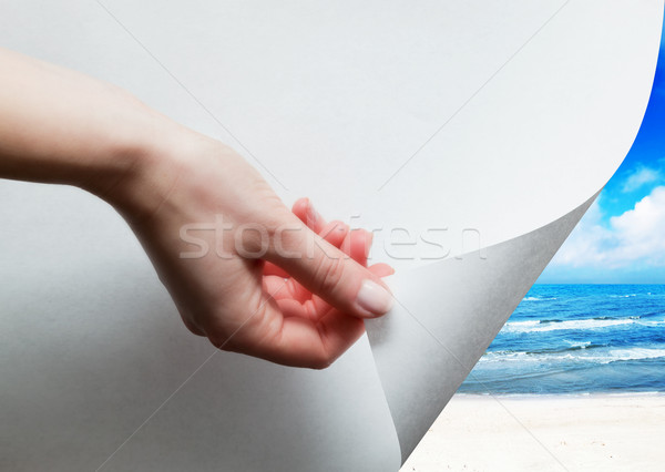 Hand pulling a paper corner to uncover, reveal sunny beach Stock photo © photocreo