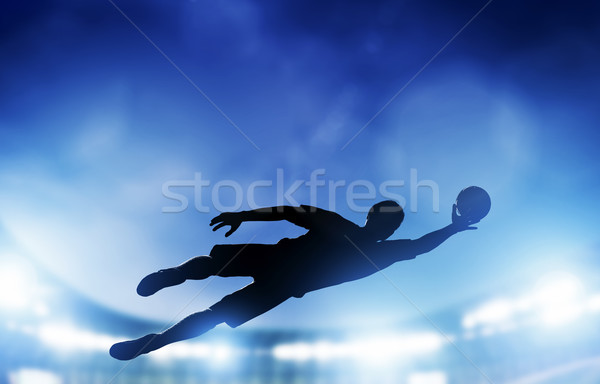 Football, soccer match. A goalkeeper jumping saving the ball from goal. Stock photo © photocreo