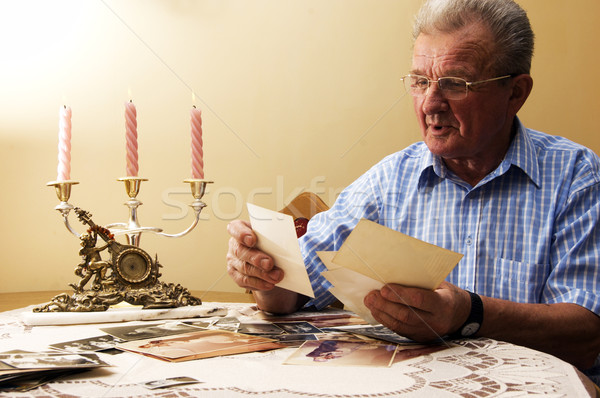 Senior man looking at old photographs. Stock photo © photocreo