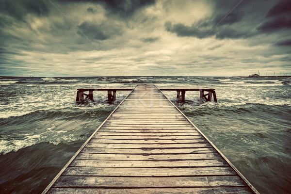 Stock photo: Old wooden jetty during storm on the sea. Dramatic sky with dark, heavy clouds