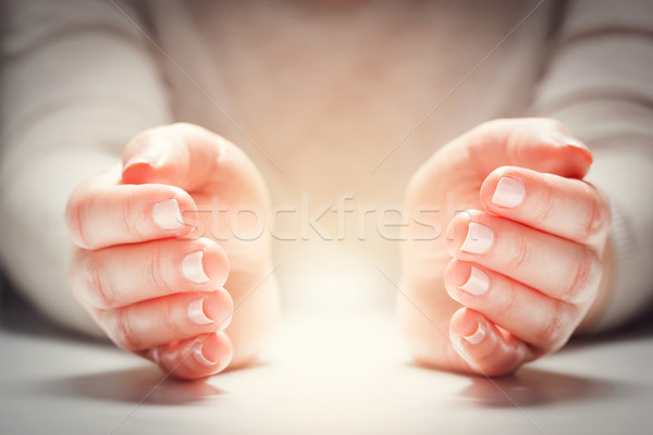 Light between woman's hands in gesture of protection, care. Stock photo © photocreo
