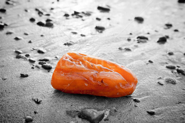 Stock photo: Amber stone on the beach. Precious gem, treasure concept