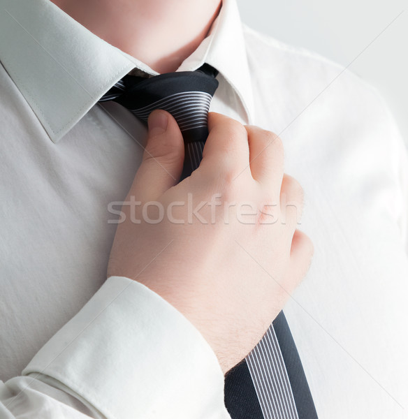 Stock photo: Businessman adjusting his tie, close-up. 