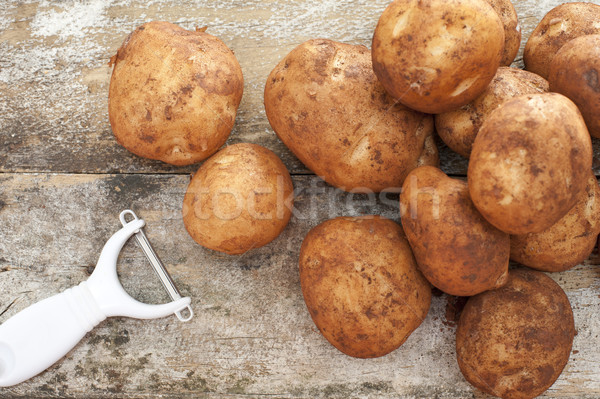 Pile of farm fresh potatoes with dirt and peeler Stock photo © photohome