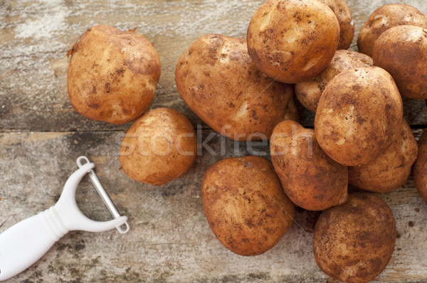 Pile of round baking potatoes beside peeler Stock photo © photohome