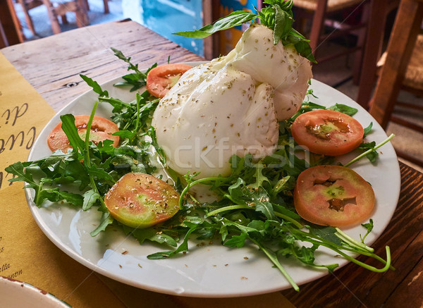 Burrata of Puglia seasoned and piled with wild rocket salad. Stock photo © Photooiasson