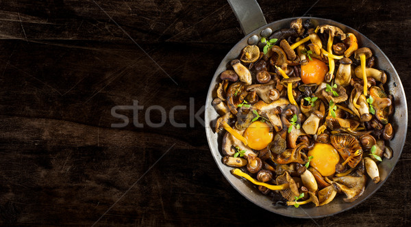 Frying pan steel with mushrooms and soft egg yolks. Stock photo © Photooiasson