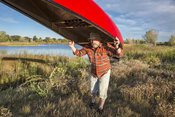 Stock photo: portaging canoe on a lake shore