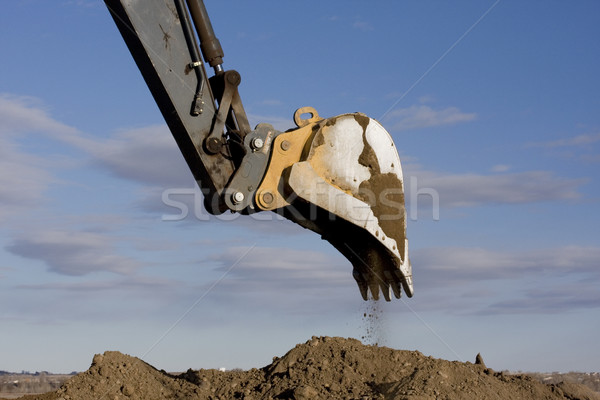 Excavator arm and scoop digging dirt at construction site Stock photo © PixelsAway