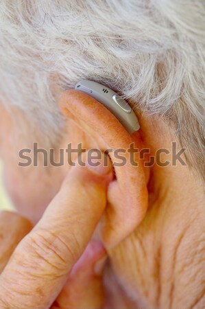 senior woman inserting hearing aid in her ears Stock photo © pixinoo
