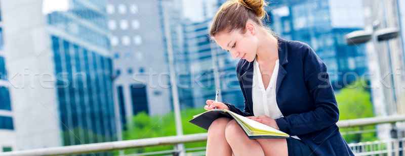 Stock photo: dynamic young executive taking notes on her agenda