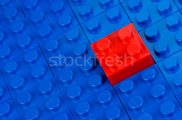 Stock photo: Red building block in a field of blue one