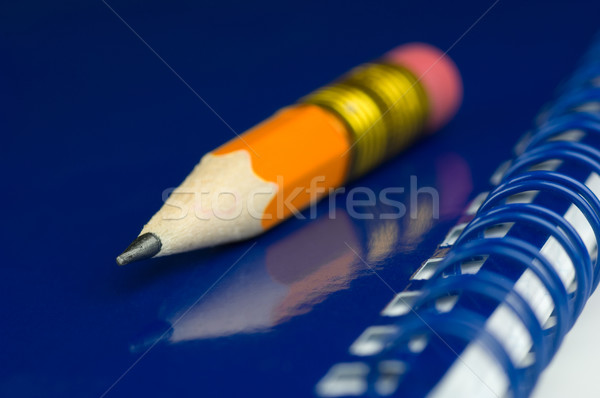 Short orange pencil on a blue notepad Stock photo © pixpack