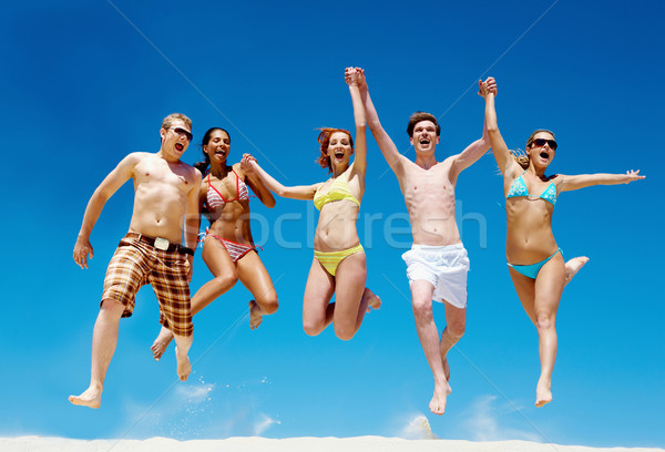 Freudige Team Freunde springen Sandstrand schreien Stock foto © pressmaster