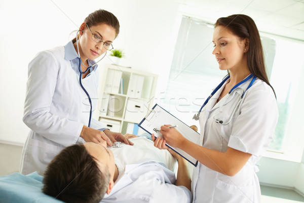 Vrouwelijke artsen onderzoeken patiënt luisteren vrouw Stockfoto © pressmaster