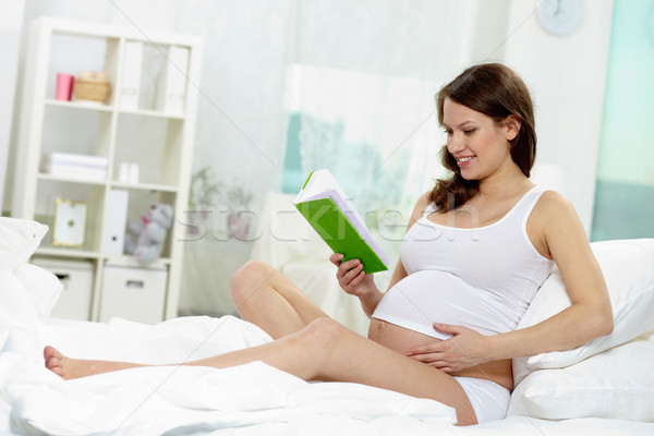 Szülés fotó boldog terhes nő olvas ágy Stock fotó © pressmaster