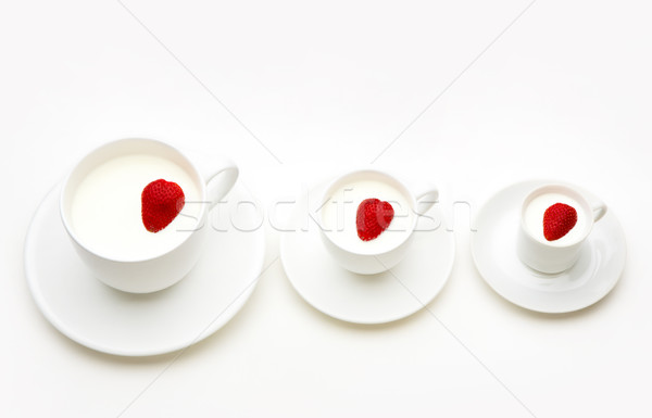 Three white cups of milk with heartshaped berries inside them Stock photo © pressmaster