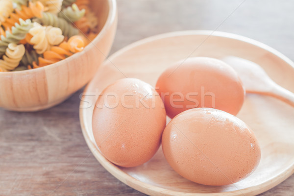 Fresh eggs on wooden plate with fusili Stock photo © punsayaporn