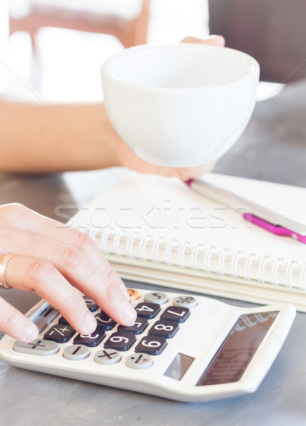 Woman's hands holding coffee cup and press calculator Stock photo © punsayaporn