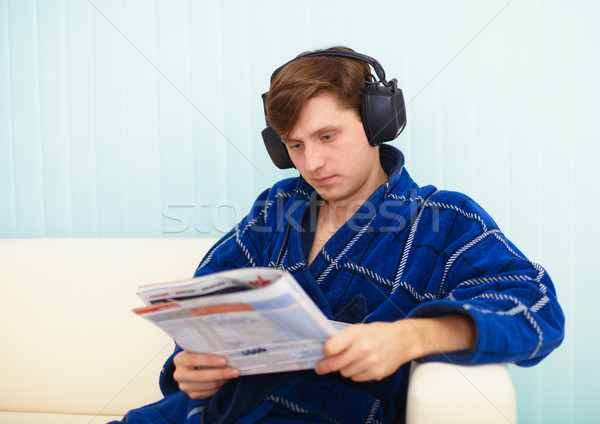 Person in big ear-phones on sofa reads newspaper Stock photo © pzaxe