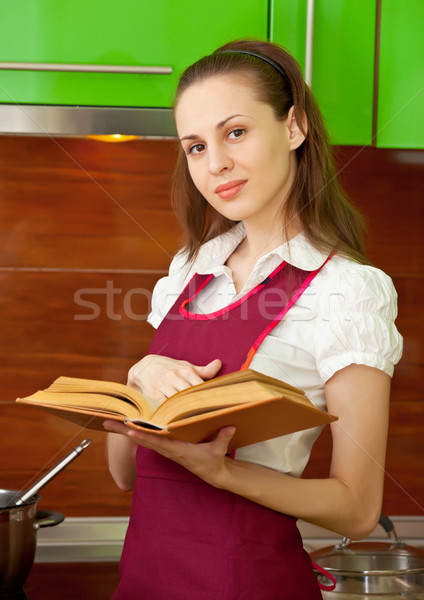 Stock photo: Woman reading a cookbook on kitchen