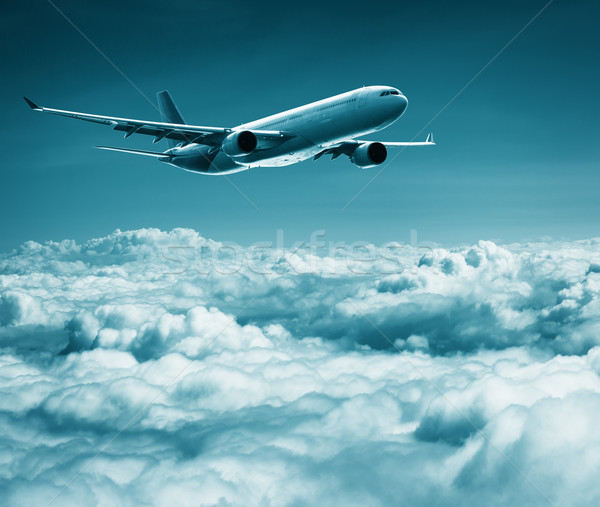 Passenger plane flies over cumulus clouds Stock photo © pzaxe