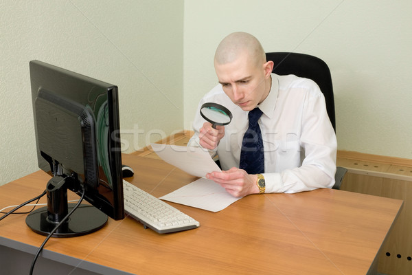 Businessman with a magnifier on a workplace Stock photo © pzaxe