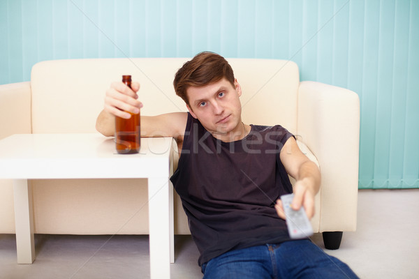 Drunk guy with bottle of beer, TV changes channels Stock photo © pzaxe