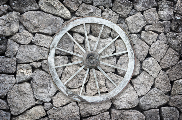 Wooden wagon wheel on a stone back ground. Stock photo © pzaxe