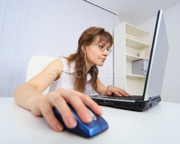 Amusing woman attentively studies Internet by means of laptop Stock photo © pzaxe