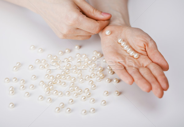 Female hands collecting beads from pearls Stock photo © pzaxe