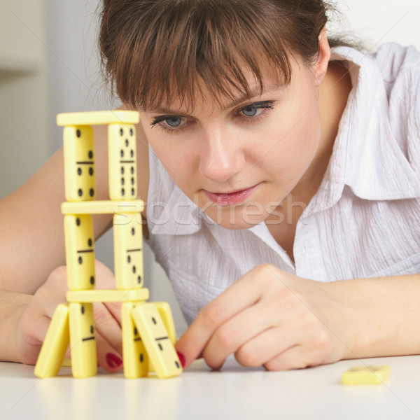 Young woman accurately builds tower of dominoes Stock photo © pzaxe