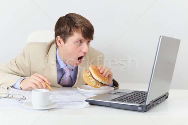 Comic clerk eats sandwich looking at screen Stock photo © pzaxe