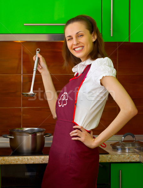 Stock photo: Cheerful young woman preparing food on kitchen