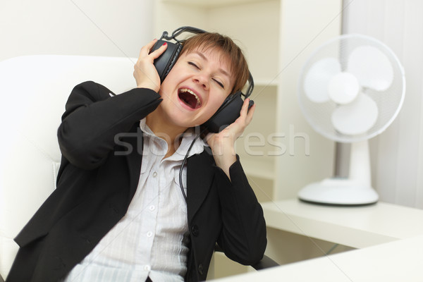 Young woman with ear-phones on head sings on a workplace Stock photo © pzaxe
