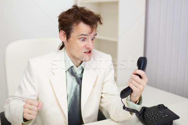 Person emotionally communicates with phone at office Stock photo © pzaxe