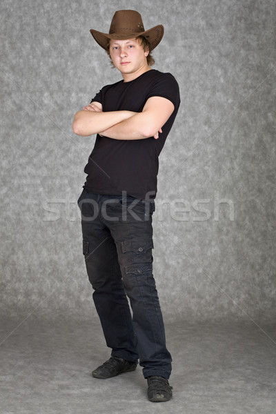 Young guy in cowboy hat standing on a grey background Stock photo © pzaxe