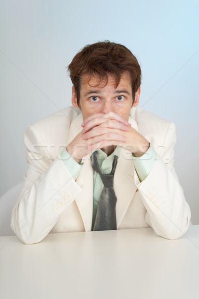 Young sorrowful person in white suit sits at table Stock photo © pzaxe