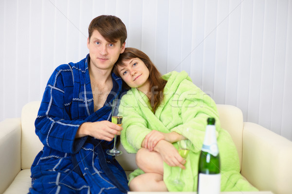 Young couple in dressing gowns sitting on couch with fizz Stock photo © pzaxe