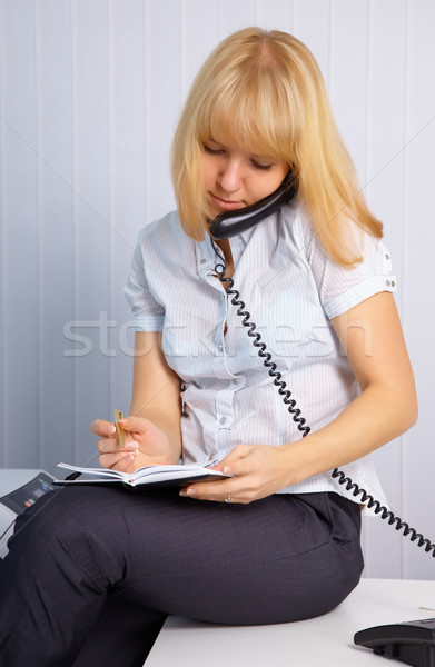 Secretary takes calls while sitting on table Stock photo © pzaxe