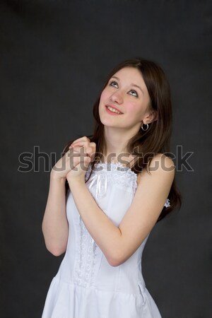 Stock photo: Pensive beautiful girl in white dress on black background