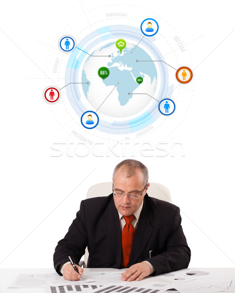 Stock photo: businessman sitting at desk with a globe and social icons