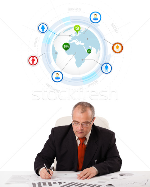 businessman sitting at desk with a globe and social icons Stock photo © ra2studio