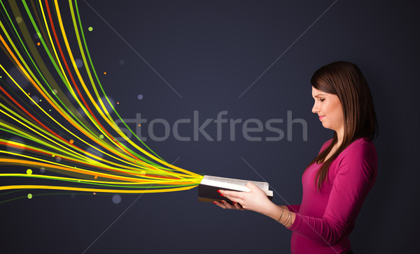 Pretty young woman reading a book while colorful lines are comin Stock photo © ra2studio
