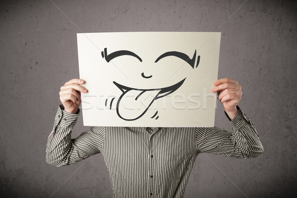 Businessman holding a paper with funny smiley face in front of h Stock photo © ra2studio