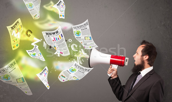 Guy yelling into loudspeaker and newspapers fly out Stock photo © ra2studio