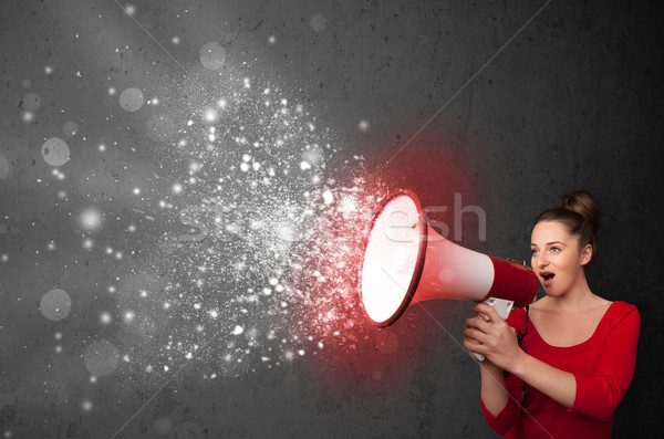 Woman shouting into megaphone and glowing energy particles explo Stock photo © ra2studio