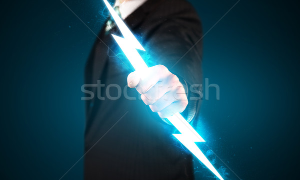 Business man holding glowing lightning bolt in his hands Stock photo © ra2studio