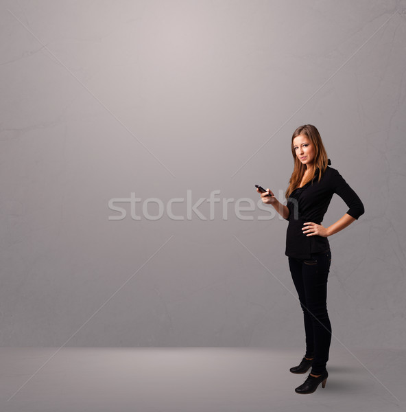 young lady standing and holding a phone with copy space Stock photo © ra2studio
